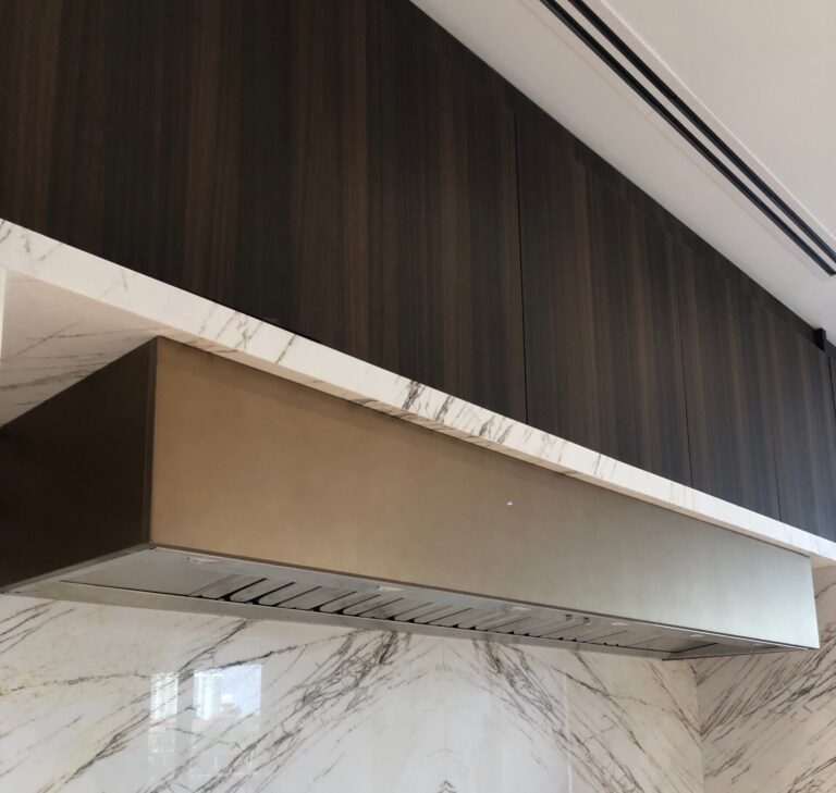 Hidden kitchen ventilation with range hood liner inside custom hood enclosure.
