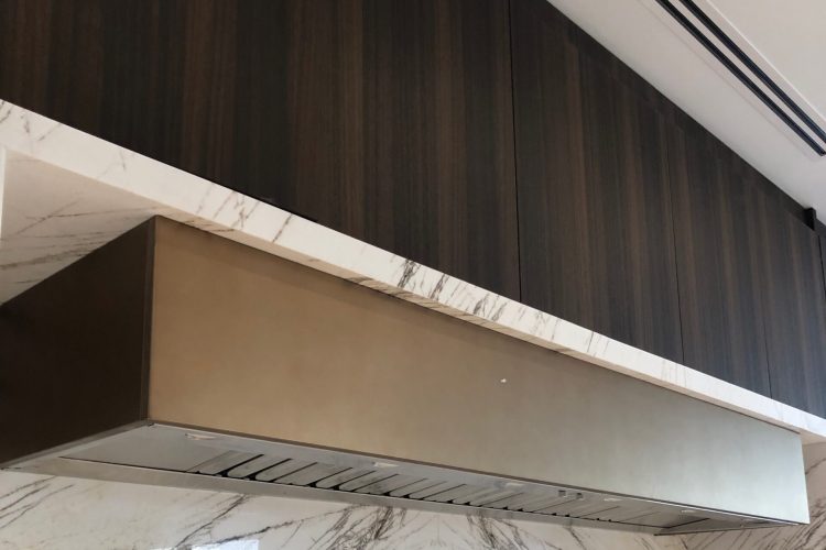 Hidden kitchen ventilation with range hood liner inside custom hood enclosure.